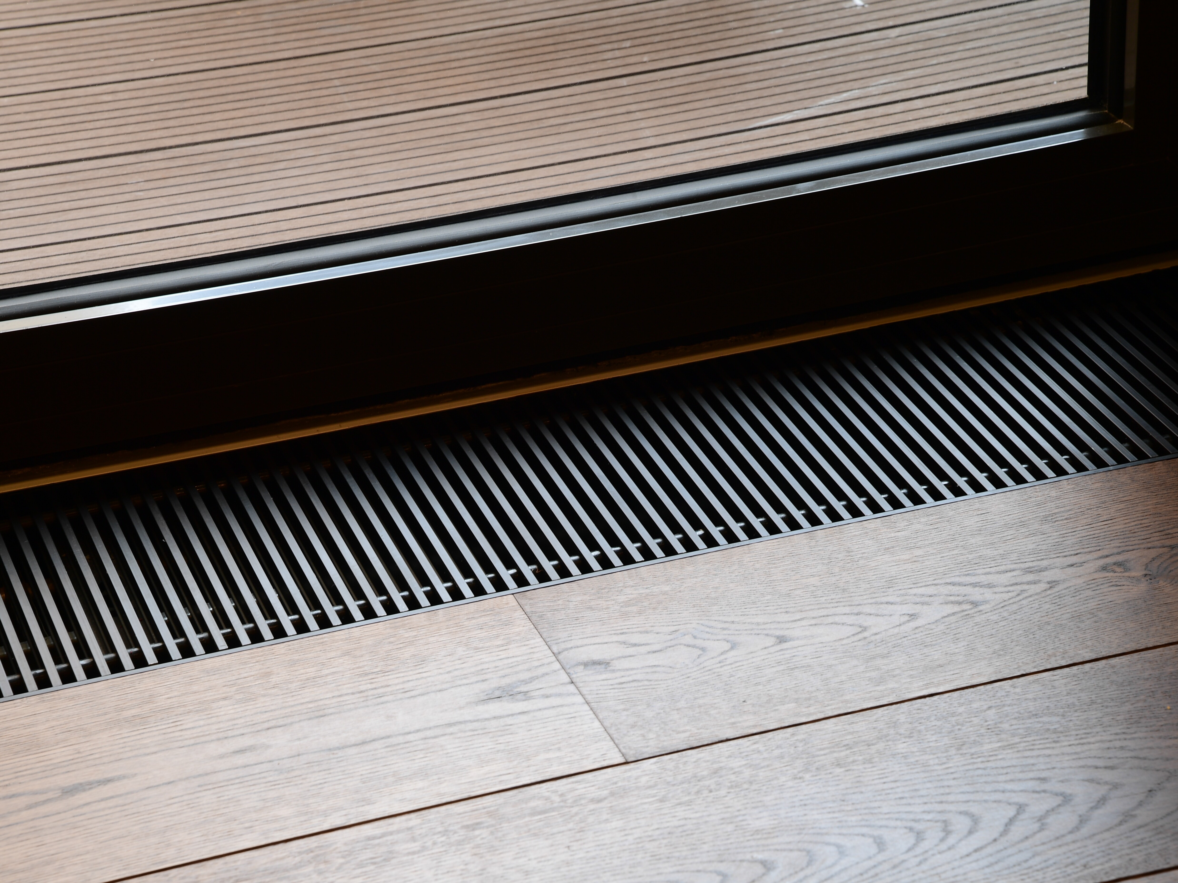 SPC trench heating grille set into a timber floor alongside full height glazing at The Grand York Hotel